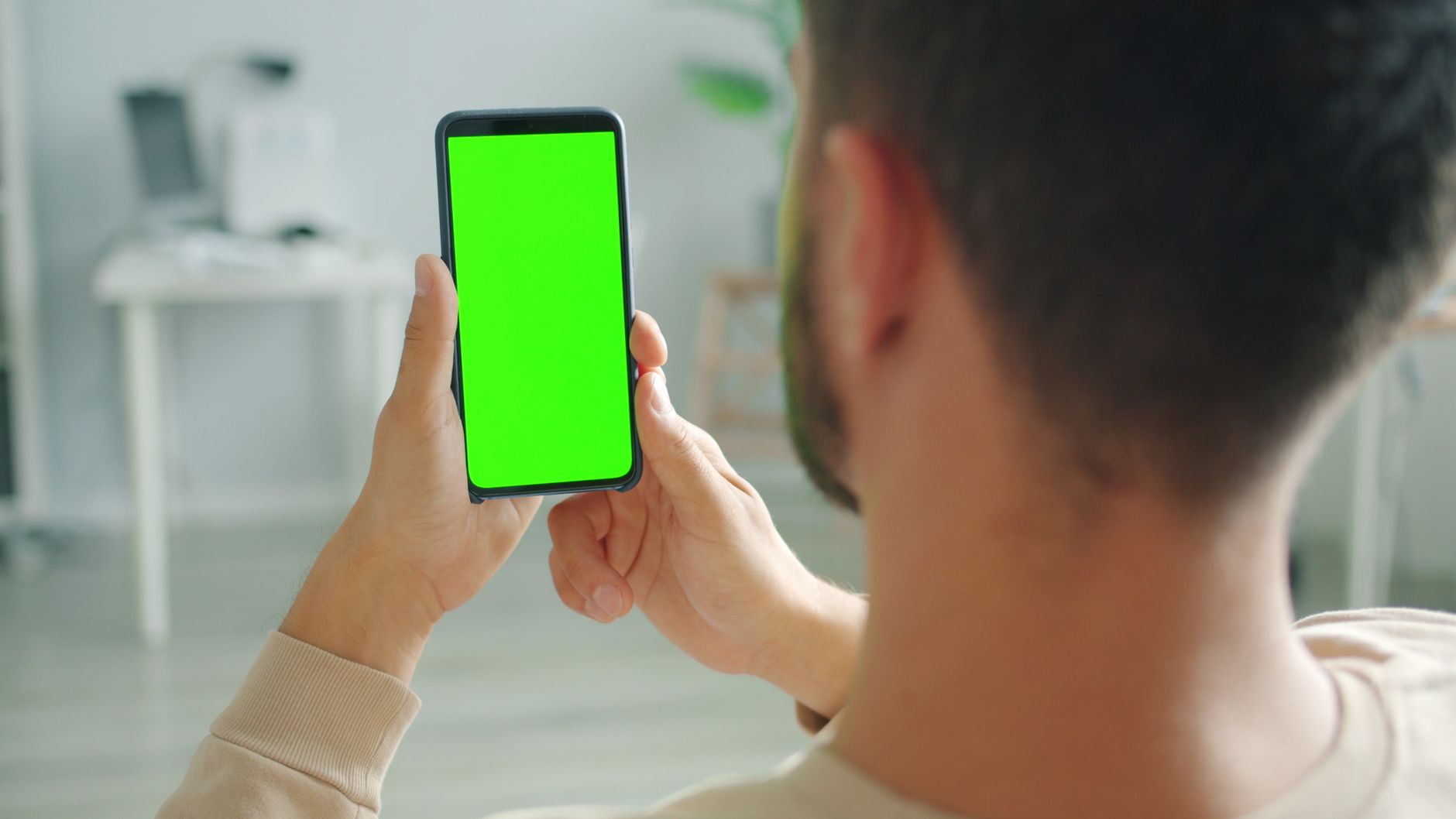 Real still of a student mid-gesture in their home office, clean play button overlay, looks like the user snapped it themselves on a phone, not a polished stock photo