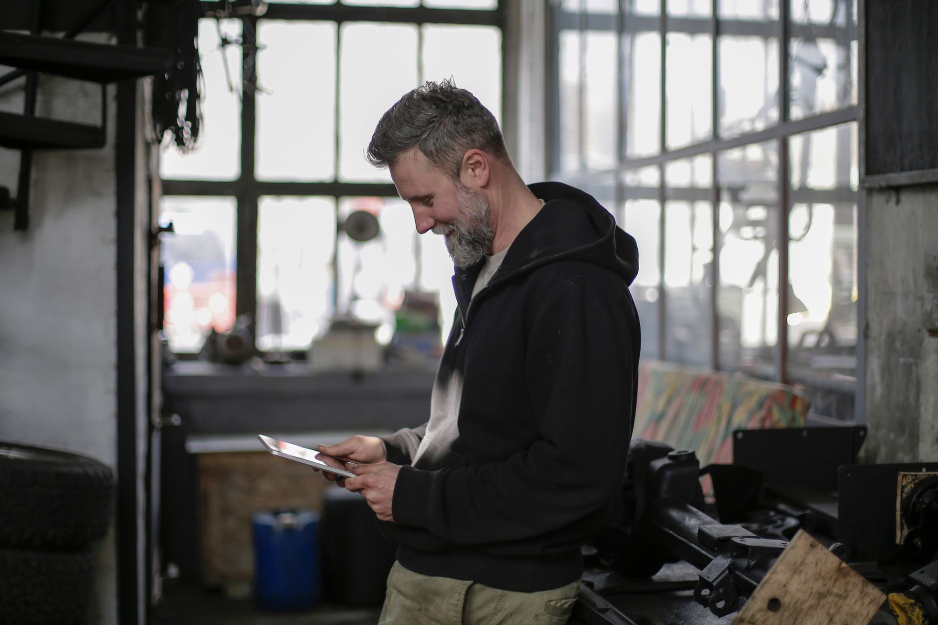 Real still of a student standing in a garage workshop, clean play button overlay, looks like the user snapped it themselves on a phone